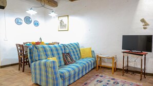 A living room with a sofa, a television, and a dining table with chairs. - Gorgeous apartment in Roccastrada with house a panoramic view (Roccastrada)