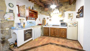 A rustic kitchen with exposed stone walls, wooden beams, a built-in oven, a tiled backsplash, and a vintage refrigerator. - Gorgeous apartment in Roccastrada with house a panoramic view (Roccastrada)