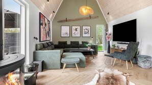 A modern living room with a large sectional sofa, a flat-screen TV, and a fireplace. - Lovely home in Væggerløse with sauna (Væggerløse)