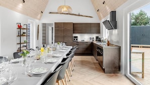 A modern kitchen with dark wood cabinets, a built-in oven, and a large island with a sink. - Lovely home in Væggerløse with sauna (Væggerløse)
