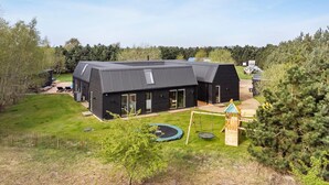 A modern black house with a large deck and a trampoline in the yard. - Lovely home in Væggerløse with sauna (Væggerløse)