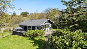 A small cabin with a porch, surrounded by lush greenery and trees. - Nice home in Esbjerg V with WiFi (Esbjerg V)