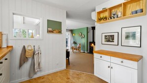 A hallway with white paneled walls, a wooden bench, a fireplace, and a shelf with decorative items. - Nice home in Esbjerg V with WiFi (Esbjerg V)