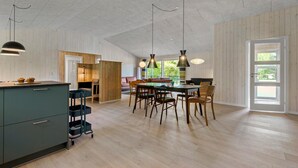 A spacious kitchen with a dining area, wooden panel walls, and large windows. - Awesome home in Oksbøl with sauna (Oksbøl)