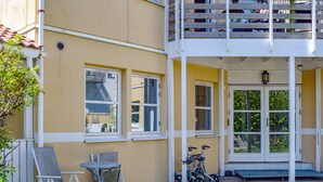 En gul bygning med balkon, overdækket veranda og en cykel.