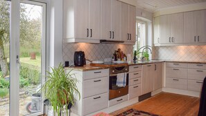 A modern kitchen with light wood cabinets, a built-in oven, and a large window overlooking a garden. - Cozy home in Hammenhög with WiFi (Hammenhög)