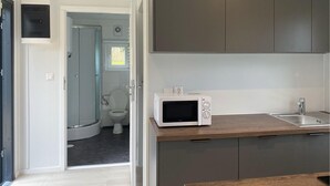 A compact kitchen with a microwave, a sink, and a small window.