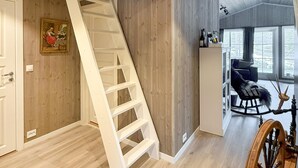 A modern interior with a wooden floor, a white staircase, a rocking chair, and a window with a view. - Stunning home in åmli with house a mountain view (Åmli)