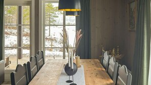 A dining room with a wooden table, chairs, a black pendant light, and a view of a snowy landscape through large windows. - Stunning home in åmli with house a mountain view (Åmli)