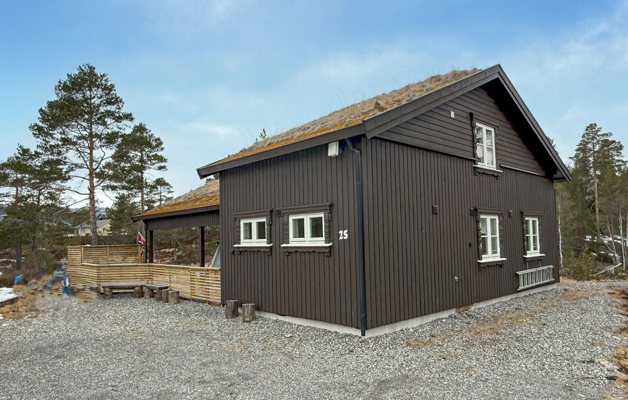 Une cabane en bois sombre, dotée d’un toit en pente et portant le numéro 25, avec deux fenêtres et un petit espace porche.