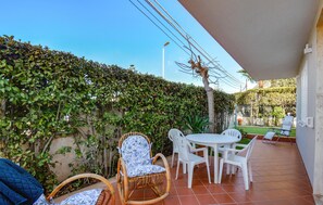 A patio with a table and chairs, surrounded by greenery and a tiled floor. - Awesome apartment in Marina di Modica (Marina di Modica)