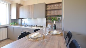 A modern kitchen with wooden cabinets, a stainless steel sink, and a dining table set with plates, glasses, and a bottle of champagne. - Pet friendly apartment (Soiano del Lago)