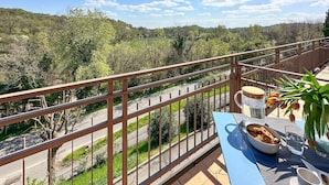 A balcony with a table set for breakfast, overlooking a road and a forested hillside. - Pet friendly apartment (Soiano del Lago)