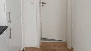 Eine weiße Tür mit silberner Klinke und Schloss, eine weiße Wand und ein Holzboden.