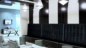 A modern waiting area with a black and white color scheme, featuring a large cushioned bench, grey upholstered chairs, and pendant lighting. - Distinct Houston Luxury Downtown W/kingbed (Houston)