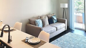 A modern living room with a sofa, dining table, and pendant lights. - Distinct Houston Luxury Downtown W/kingbed (Houston)