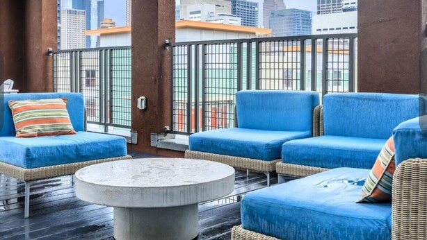 A rooftop terrace with blue cushioned seating and a round table, offering a city view. - Distinct Houston Luxury Downtown W/kingbed (Houston)