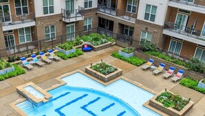 A rooftop pool area with lounge chairs and planters, surrounded by a multi-story building. - Distinct Houston Luxury Downtown W/kingbed (Houston)