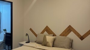 Ein Schlafzimmer mit einem Bett, einem Nachttisch, einer Lampe und einer Wand mit geometrischem Muster.