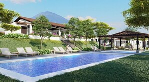 Una piscina con lettini, una zona relax coperta e un edificio sullo sfondo con vista su una montagna.
