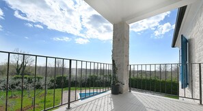 Enjoy a serene view of the pool and lush surroundings from this balcony.