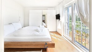 Een slaapkamer met een bed, een televisie en een raam met gordijnen.
