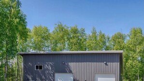 A single-story metal building with two large garage doors, a small window, and a door on the side. - Northern Lights @ Nancy Creek, Willow AK (Wasilla)