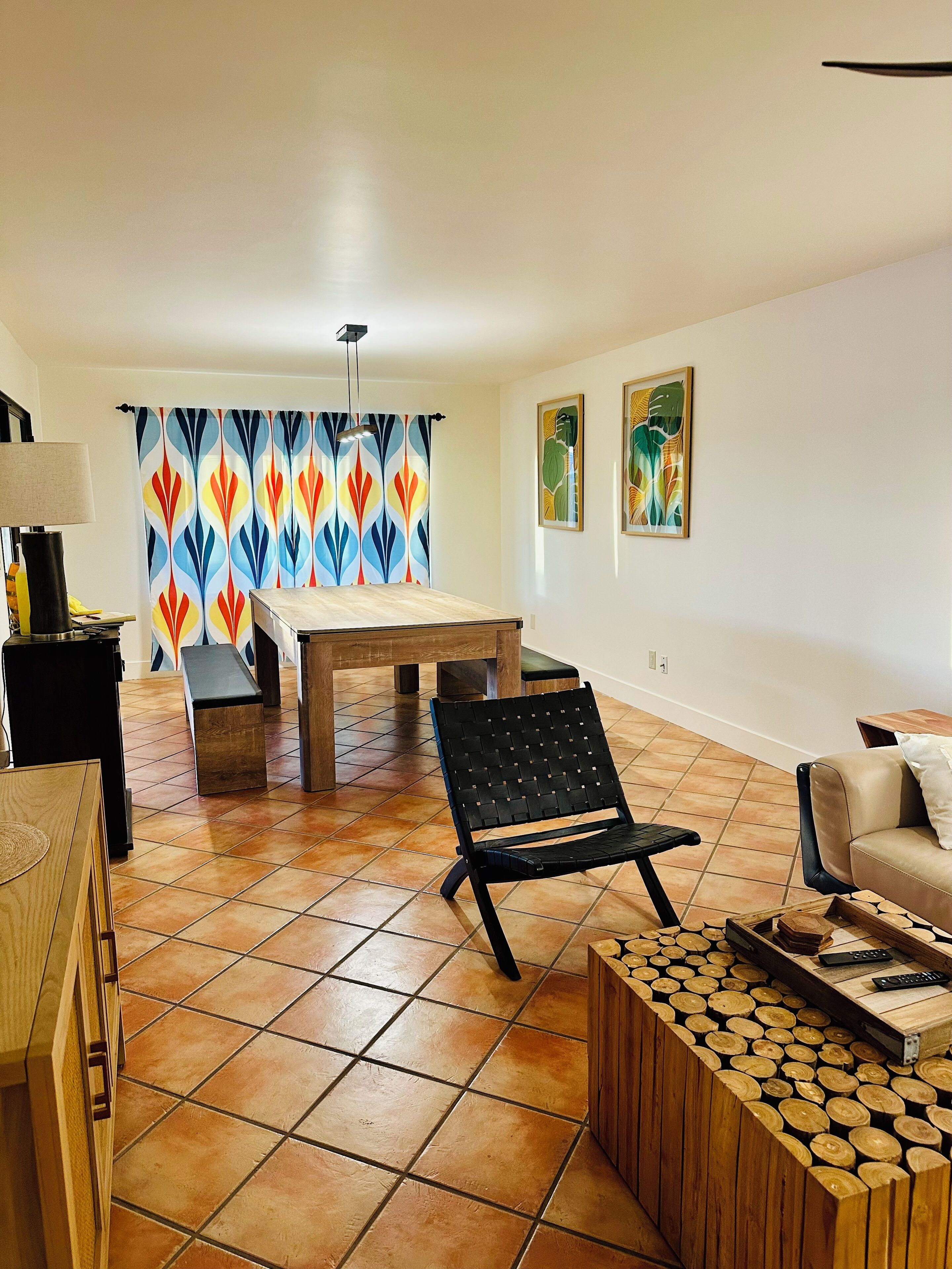 A living room with a dining area, a black woven chair, a wooden coffee table, and a sofa.