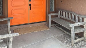Ein Backsteinbogen führt zu einer orangefarbenen Tür, an der Wand hängt ein Stierkopf.