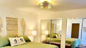 Ein Schlafzimmer mit einem großen Bett, zwei Nachttischen, einem Spiegel und einer Kronleuchter.