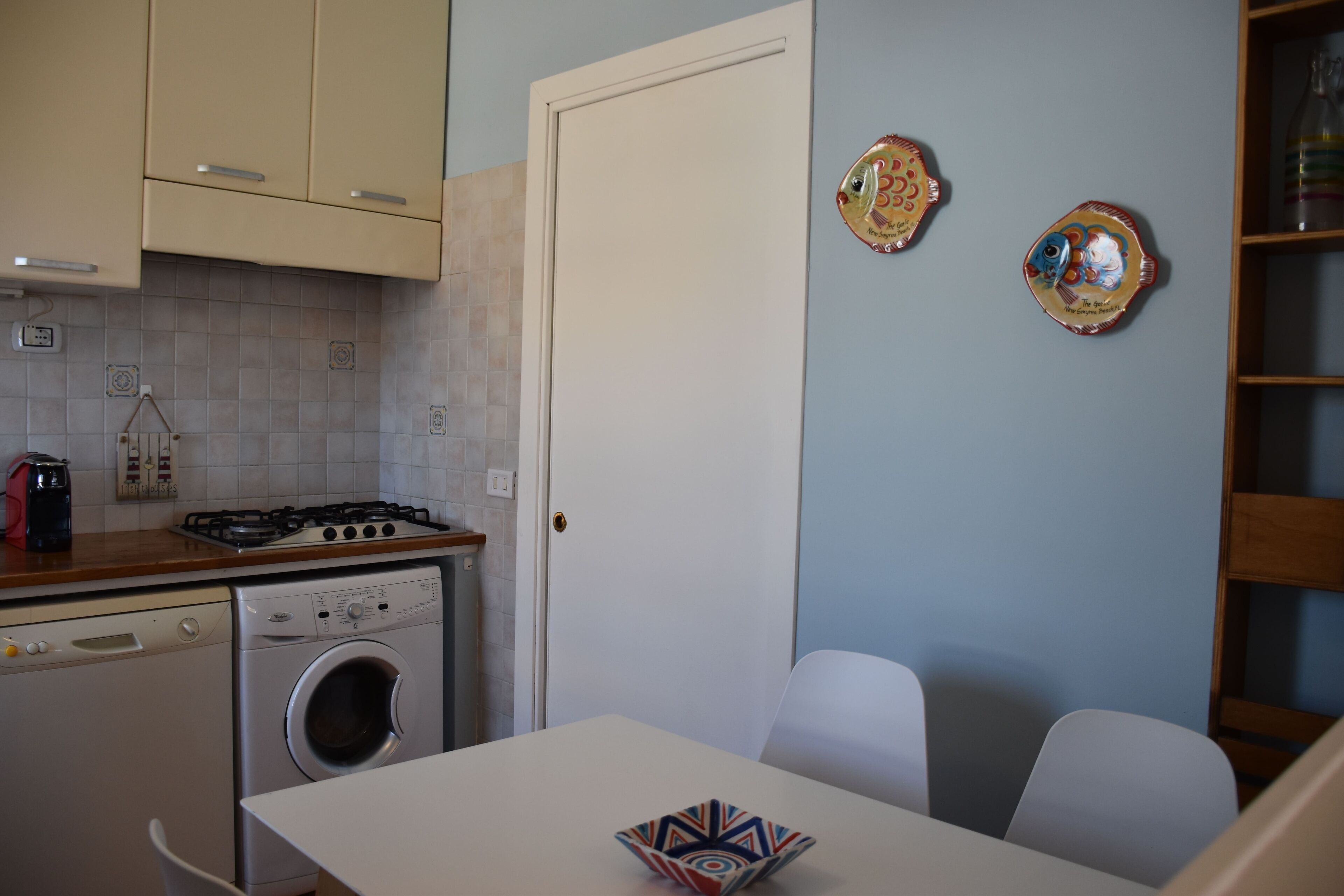 Cocina compacta con lavadora, estufa y comedor con mesa y sillas.