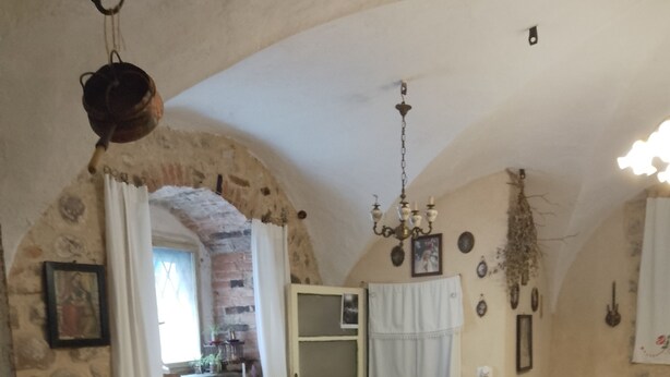 A rustic dining room with a stone wall, a chandelier, and a table set for four. - Authentic B&B Stella's House (Sabbio Chiese)