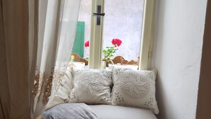 A small, cozy room with a window, a bench with cushions, and a green door. - Authentic B&B Stella's House (Sabbio Chiese)