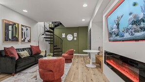 Una sala de estar moderna con un sofá negro, sillones rojos, una mesa de centro blanca y un acuario grande.