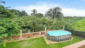 A backyard with a circular pool surrounded by a wooden fence and lush greenery. - Cozy Beach Home with Pool, Game Room & Gym – Walk to the Beach (Dorado)
