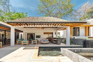 Un patio extérieur moderne doté d’une pergola, d’un espace salon et d’une petite piscine.