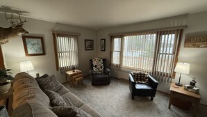 A living room with a sofa, two armchairs, a small table, and a deer head mounted on the wall. - Lake Nokomis  Cozy 2-Bed Getaway for Couples, Families & Outdoor Enthusiasts (Tomahawk)