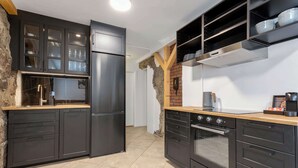 A modern kitchen with dark cabinetry, a stainless steel refrigerator, a built-in oven, and a wooden countertop. - Ranargata - Central Four Bedrooms Apartment A (Reykjavík)