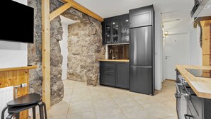A modern kitchen with a stone wall, wooden beams, a black refrigerator, and a wooden countertop. - Ranargata - Central Four Bedrooms Apartment A (Reykjavík)
