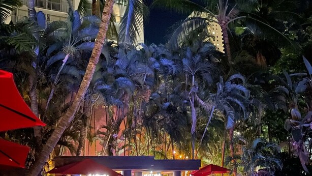 A poolside area with lounge chairs and a small building with a pool. - waikiki beach (Honolulu)