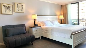 A hotel room with a bed, a nightstand, a chair, and two wall-mounted lamps. - waikiki beach (Honolulu)