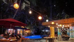 An outdoor dining area with tables and chairs, a pool, and tropical plants. - waikiki beach (Honolulu)