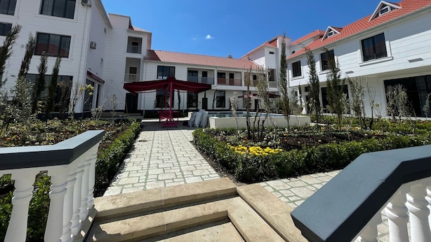 A courtyard with a red pergola, white buildings, and a paved walkway. - Magnolia Family Boutique and Spa (Ismailli)