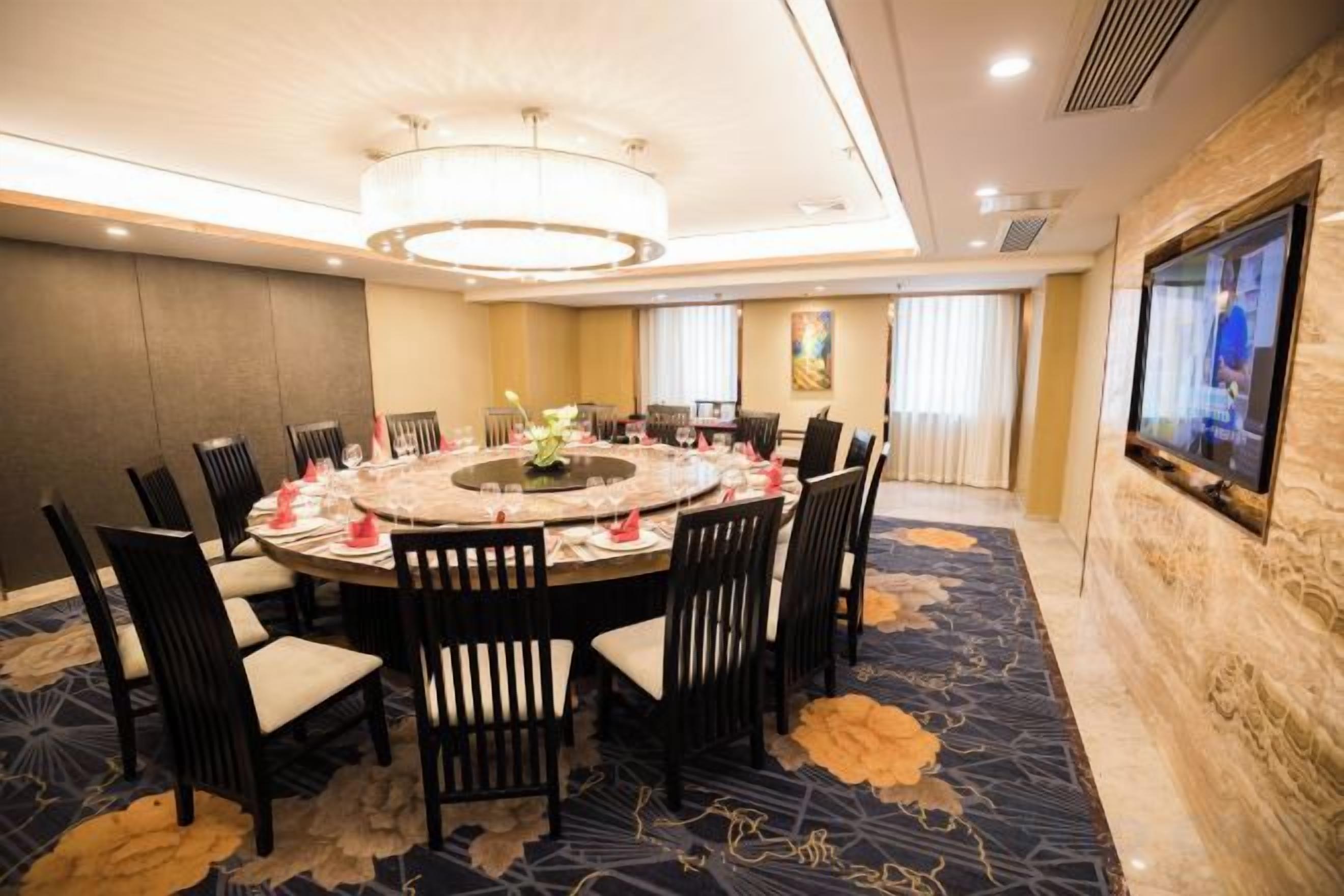 A conference room with a round table, chairs, and a television on the wall.