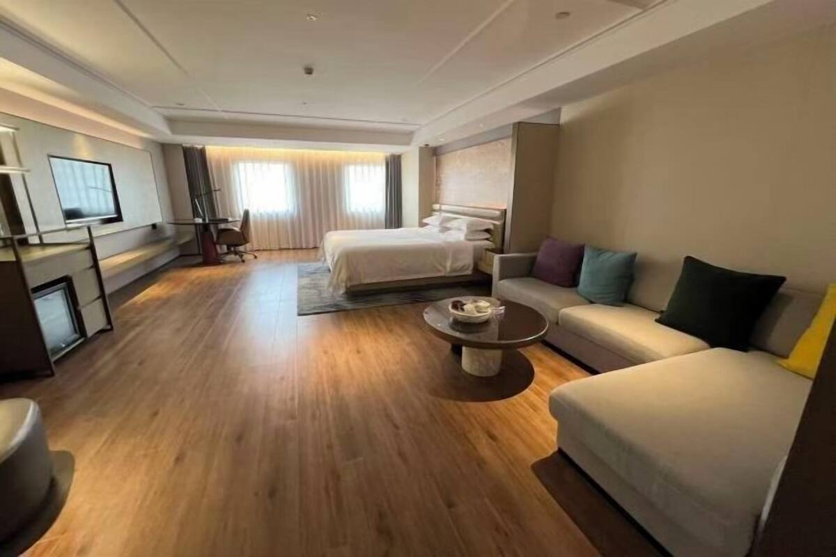 A hotel room with a bed, sofa, coffee table, TV, and a desk.