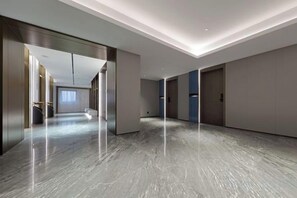 A modern hotel corridor with a polished marble floor, recessed lighting, and a view into a room with a large window. - Xingtai Business Hotel (Jinjiang)
