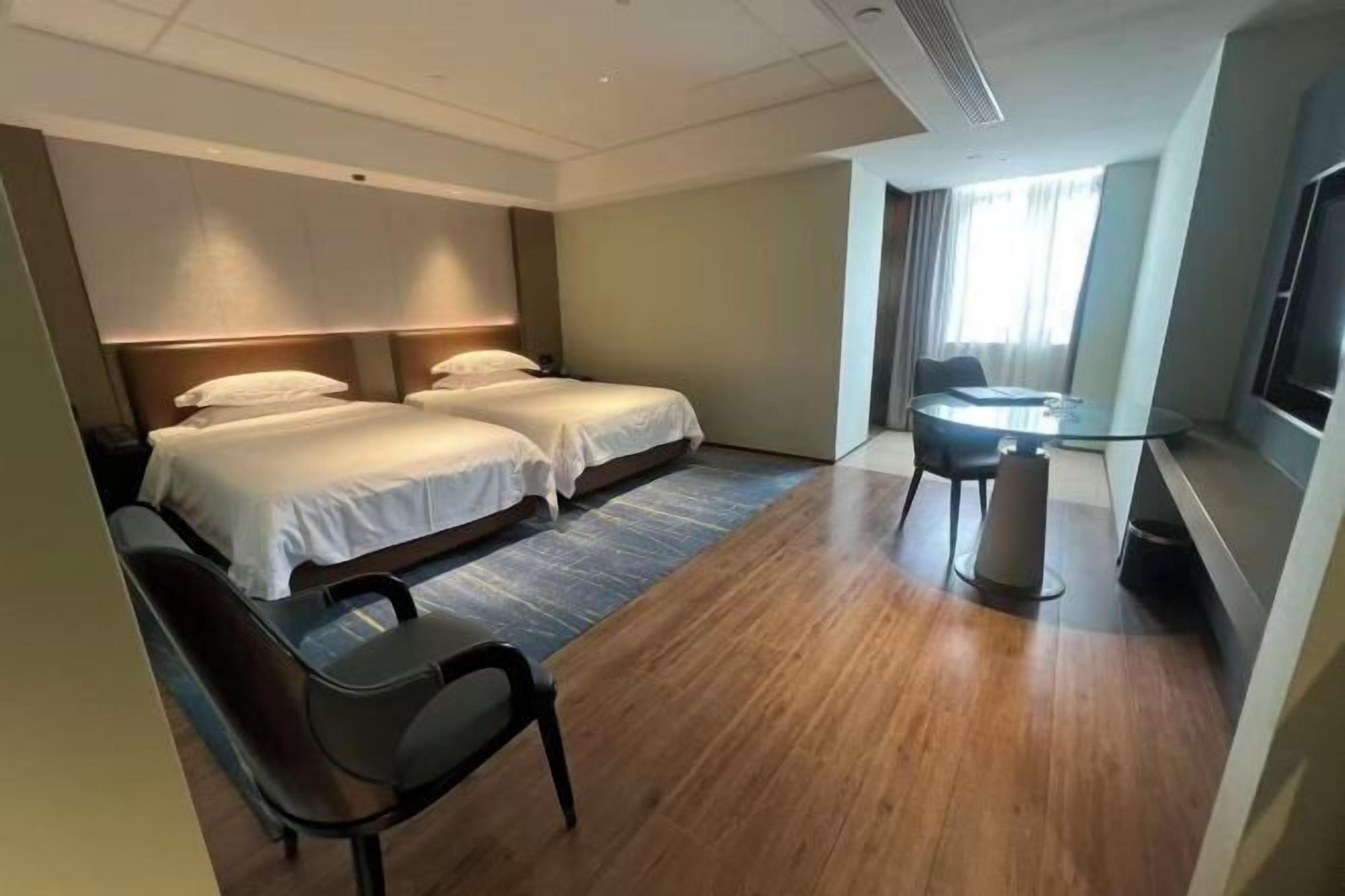 Habitación de hotel con dos camas, un escritorio, una silla y un televisor.
