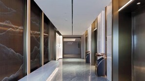 A modern hallway with elevators, marble flooring, and wall art.