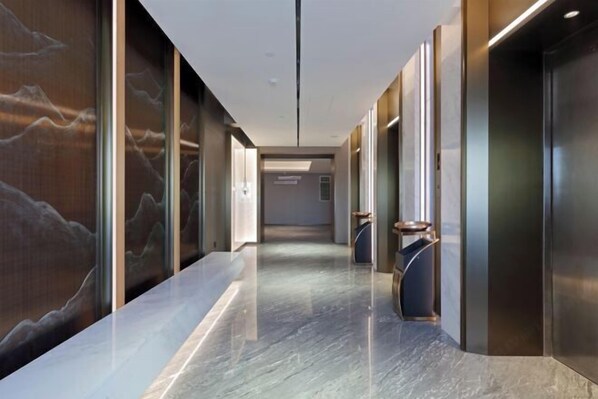 A modern hallway with elevators, marble flooring, and wall art. - Xingtai Business Hotel (Jinjiang)