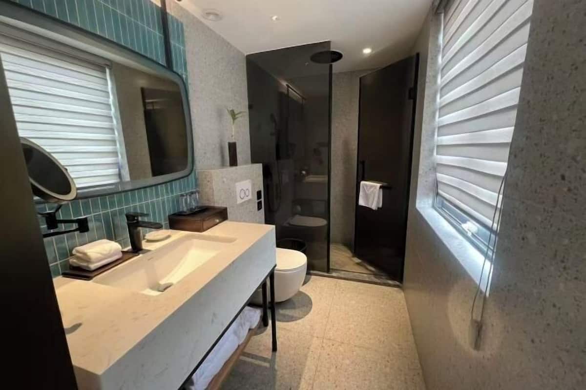A modern bathroom with a large mirror, a sink, a toilet, and a shower area.